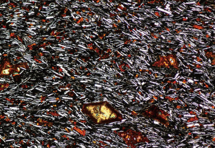 玄武洞（兵庫県 山陰海岸ユネスコ世界ジオパーク）の玄武岩の顕微鏡写真。針状の鉱物（斜長石）は溶岩
の流れた方向を示しています。